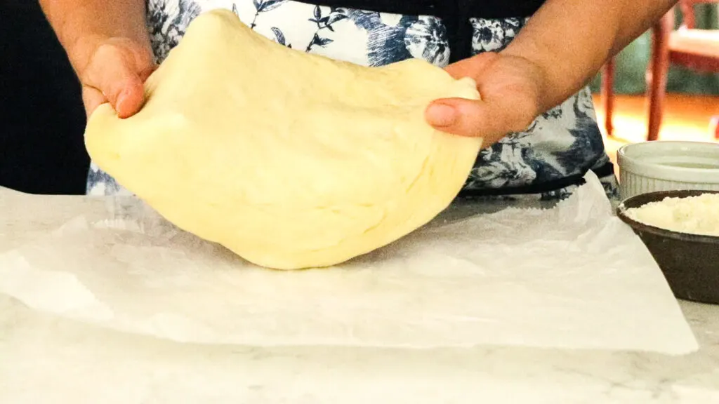 Stretch the dough over your fingers, gently pulling to make your pizza bigger.