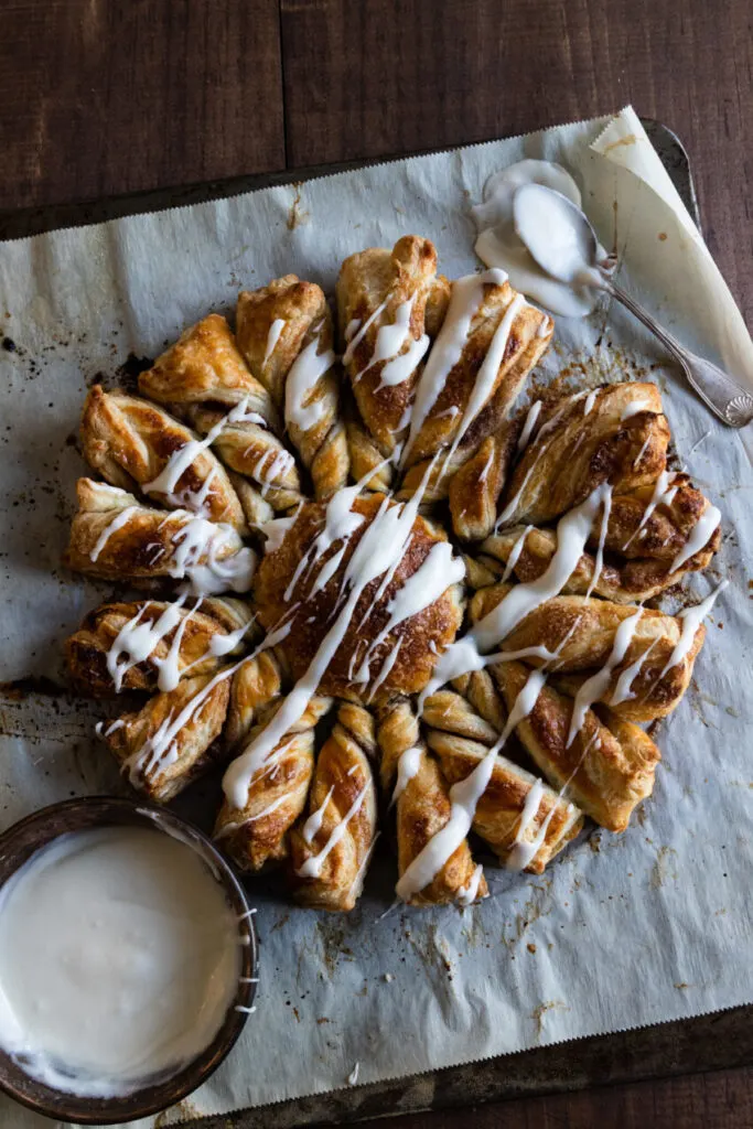 A breakfast star made of puff pastry with cinnamon sugar and glaze drizzled over the top.