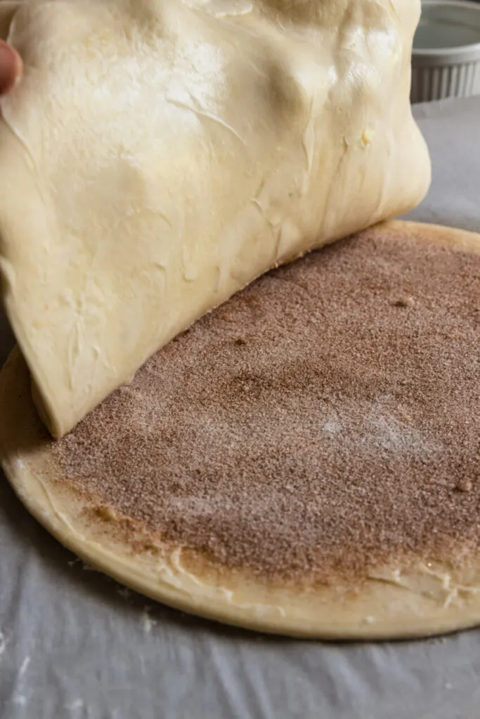 Layering the second round of pastry dough over the cinnamon sugar.