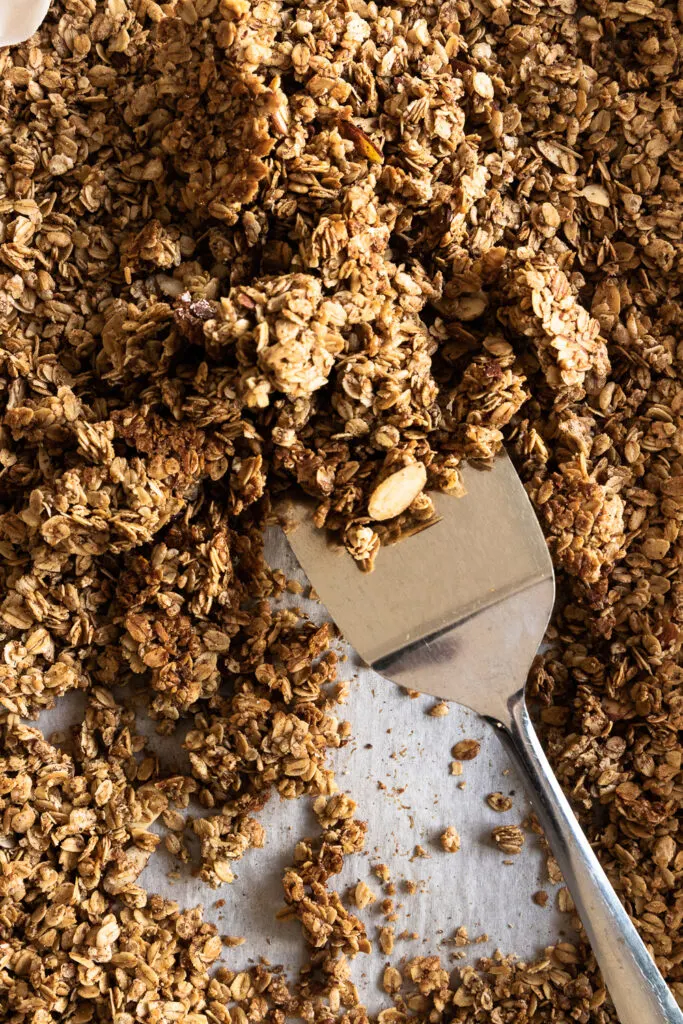 Scraping the baked granola off the sheet.