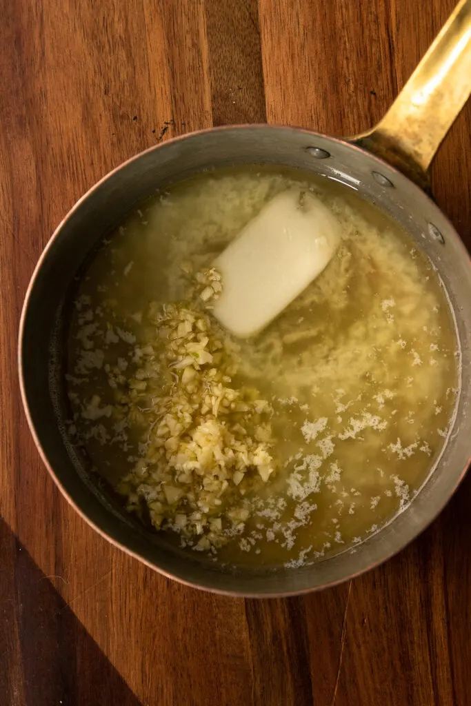 Melting butter and sauteing the garlic to top the smashed potatoes.