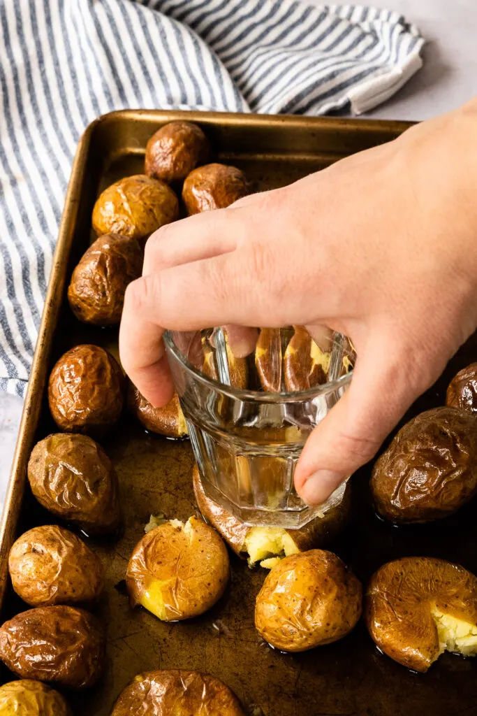 Smashing the potatoes with the bottom of a glass.
