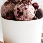 An ice cream container with several scoops of black forest ice cream on top of it.