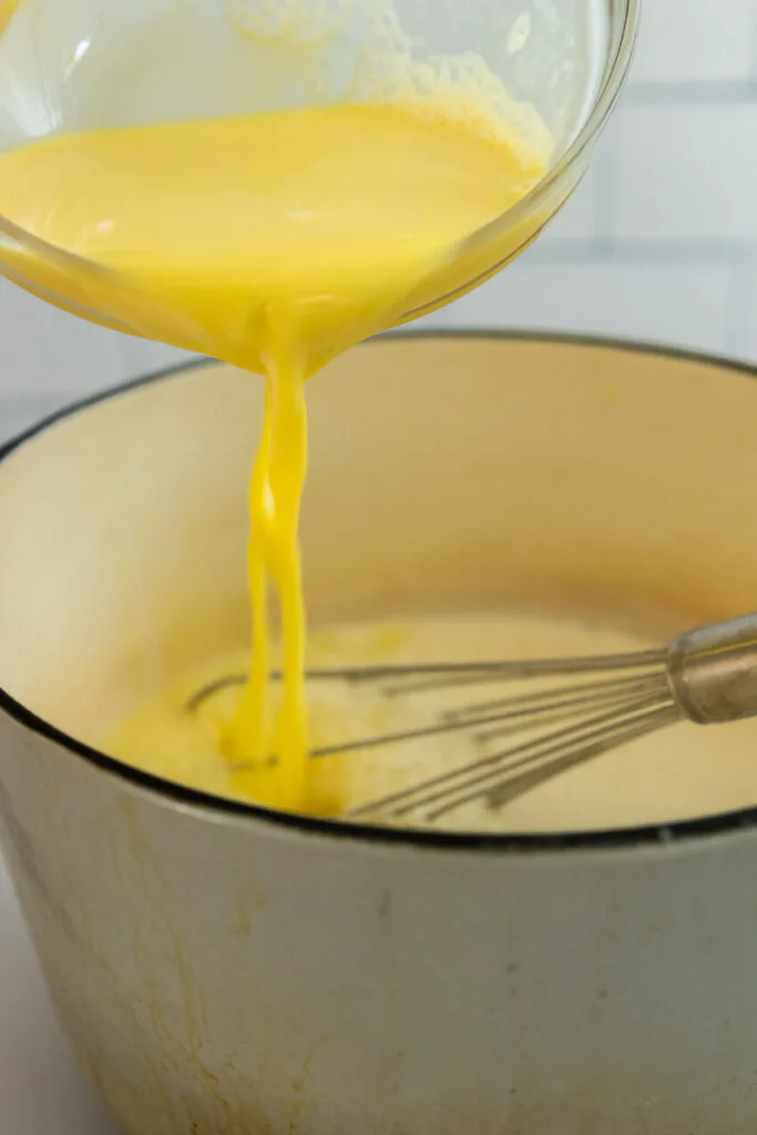 Add the egg yolks to the cream, and cook the custard until thickened.