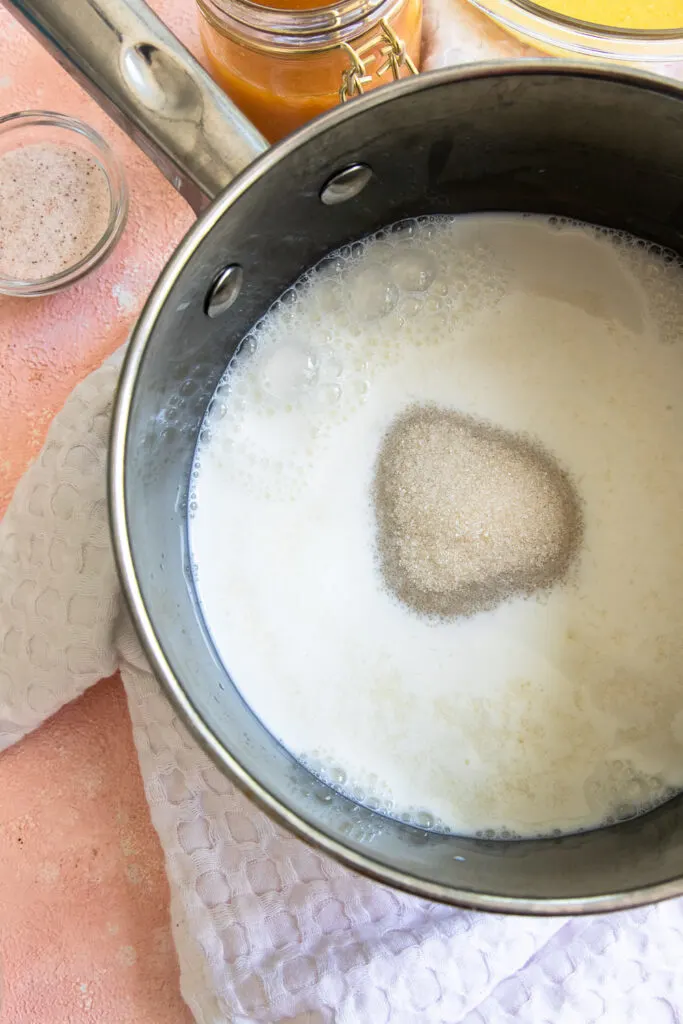 Warm the milk and sugar until it's steaming and the sugar has dissolved.