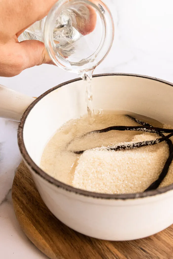 Stirring water into sugar and vanilla beans.