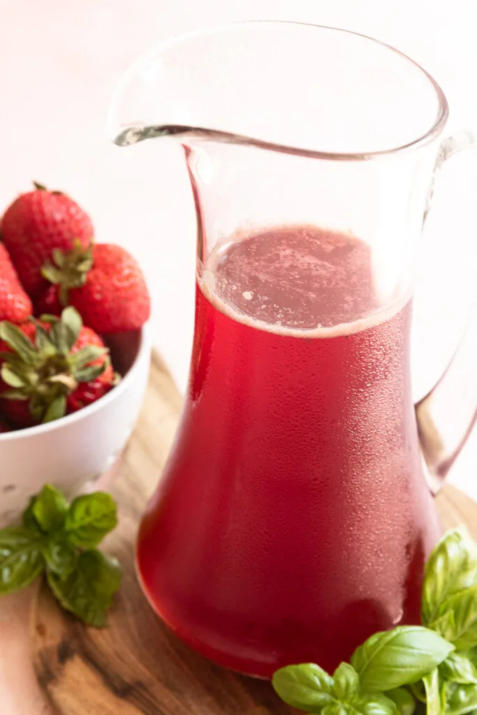 A small pitcher of strawberry basil syrup.