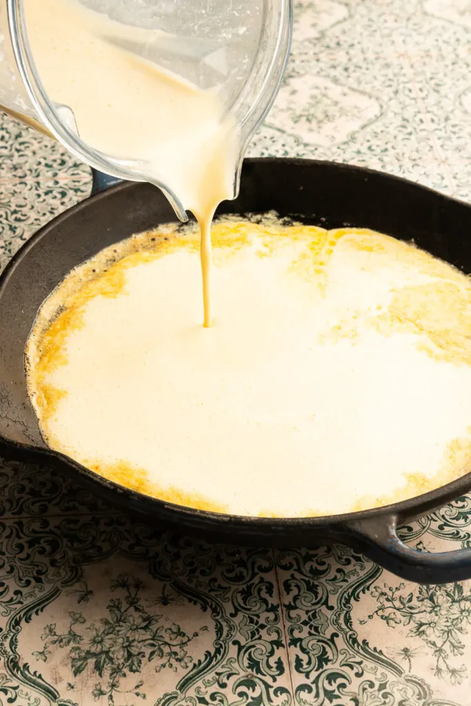 Pouring the dutch baby batter into the hot skillet.