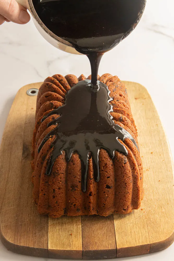 Pouring the boiled frosting over a chocolate chip pound cake.