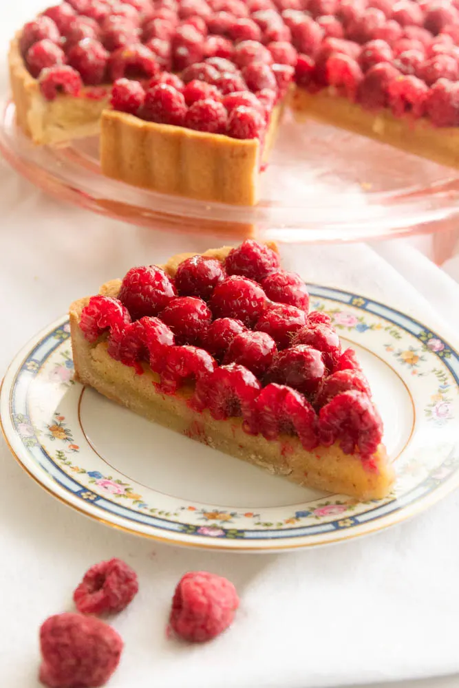 A slice of raspberry tart sitting on a plate.