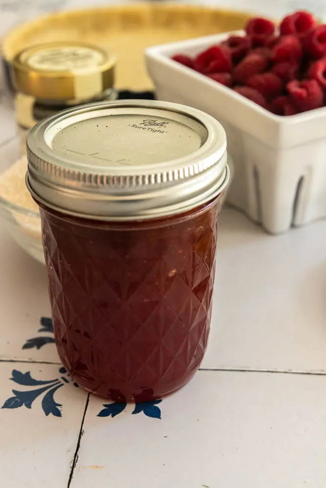 A jar of jam, ready to melt down and spread on the top of the tart.