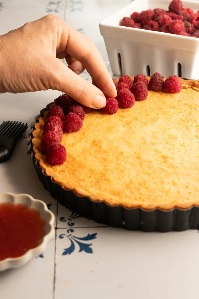 Adding the fresh raspberries to the top of the tart.