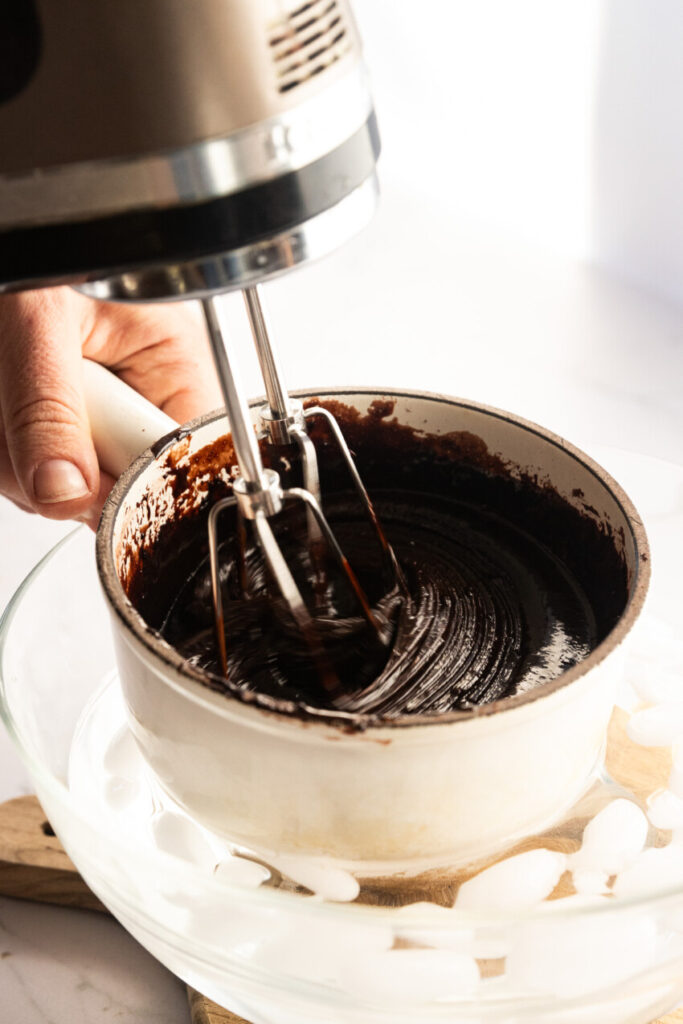 Whipping the chocolate frosting after boiling to thicken it.