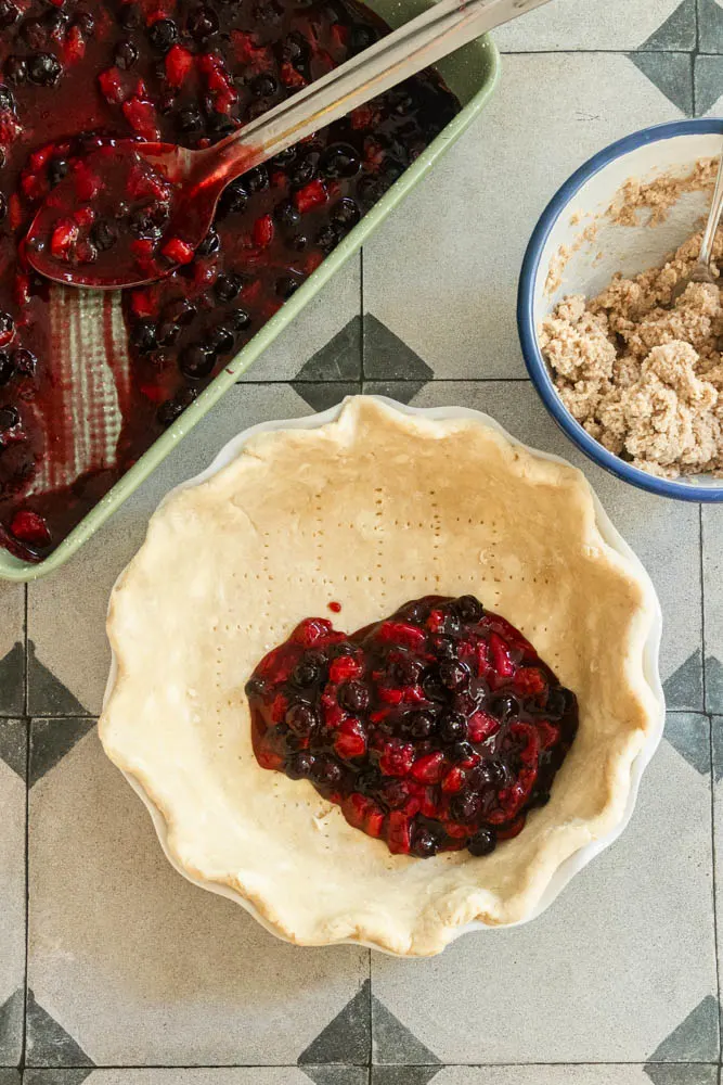 Adding the cooked berry filling to the prepared crust.