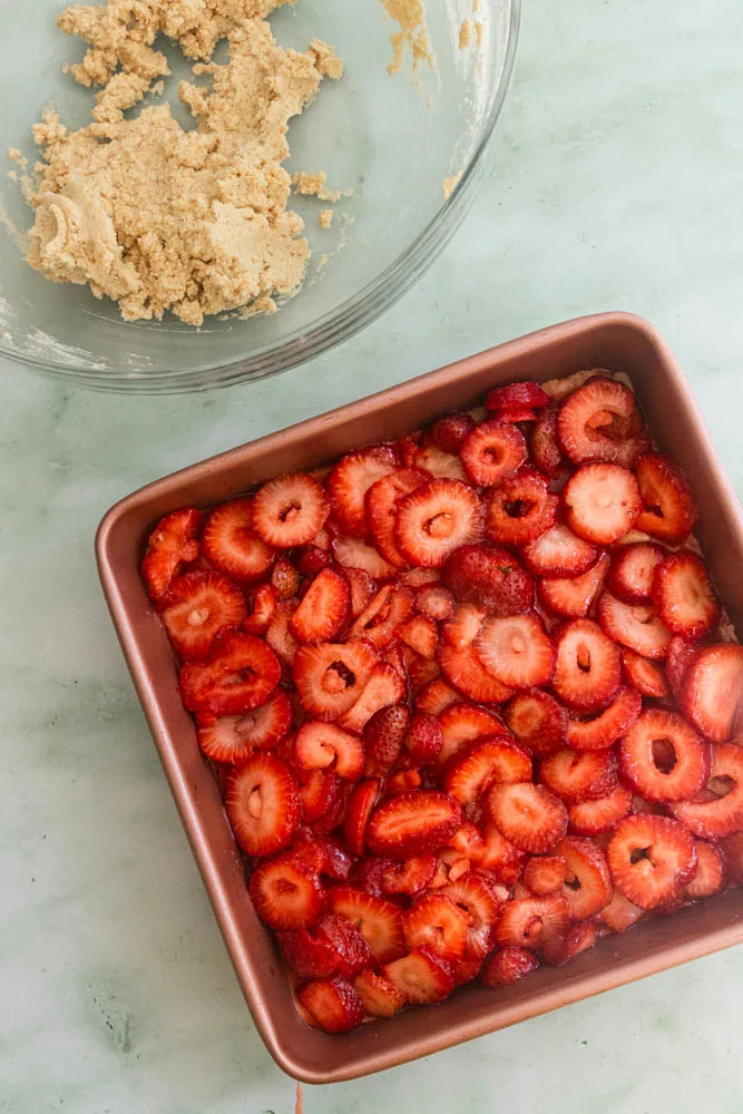 Layer the juicy strawberries onto the dough in the pan.